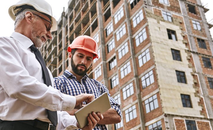 Two construction workers looking at a tablet