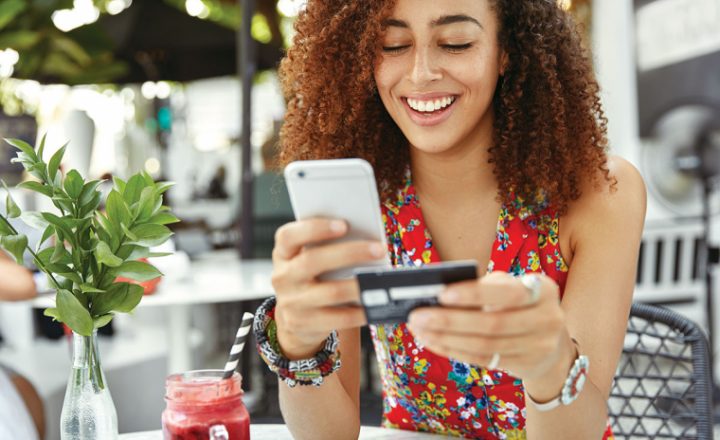 Woman holding her phone with credit card